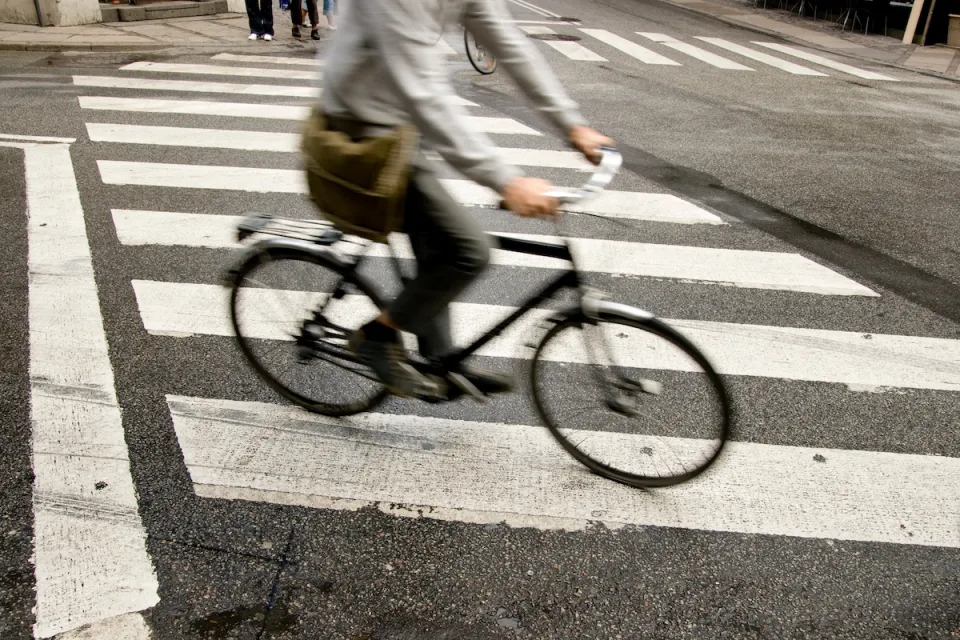 Person on bike riding across zebra crosswalk in city.